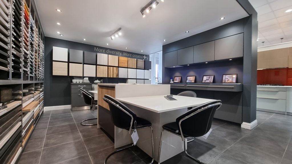 Modern showroom interior with material swatch walls and customer consultation desks. Cost Breakdown: What's the Real Investment to Buy a Kitchen & Interiors Franchise in 2026?