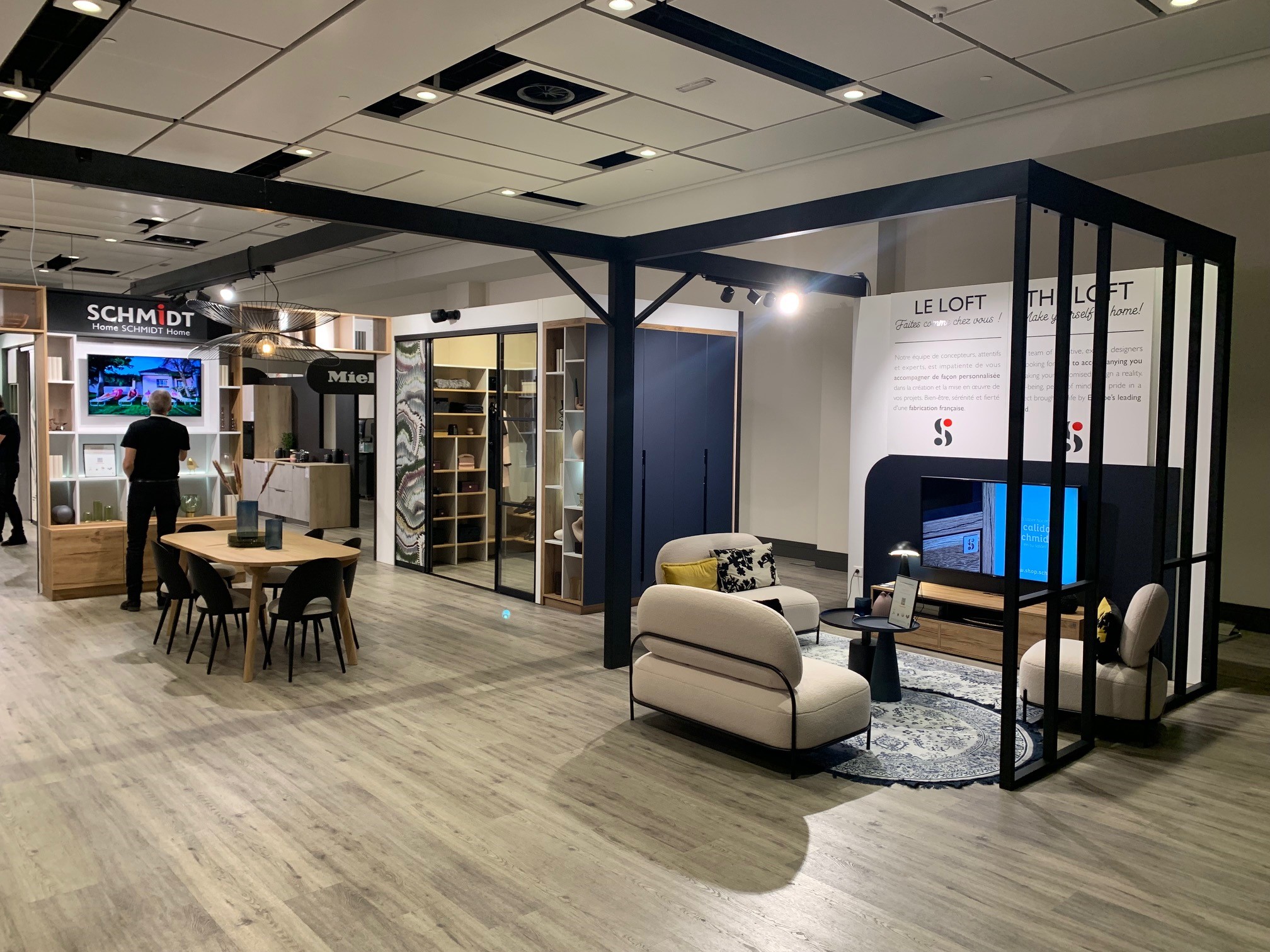Showroom 1 Schmidt showroom display featuring kitchen island, dining table, and living room. A cohesive interior scene that blends practical kitchen features with soft furnishings and designer lighting.
